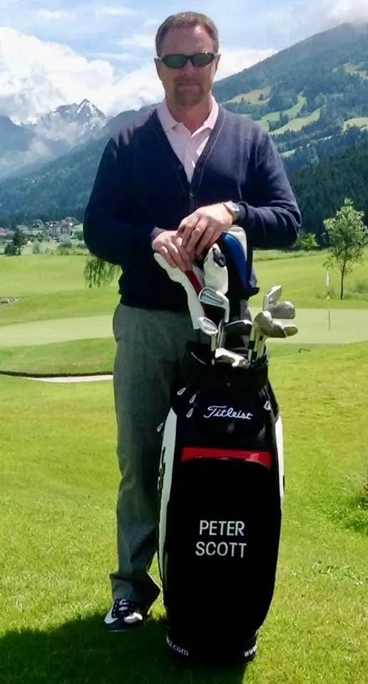 Golfer standing on course with golf bag.
