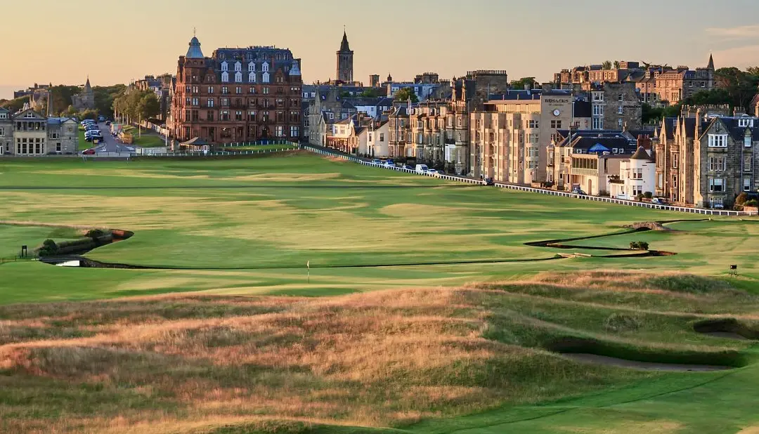 Golf course with historic buildings in background.