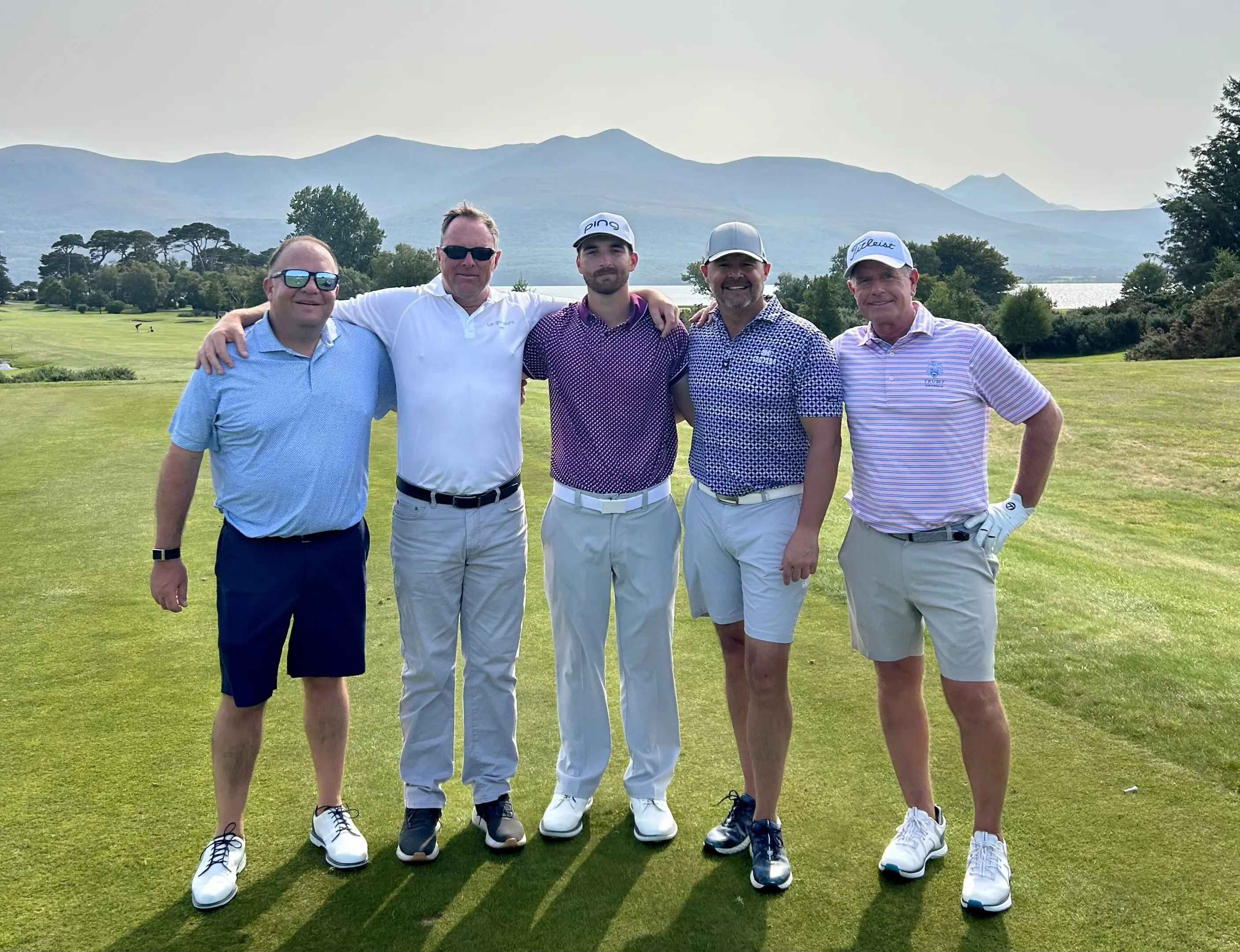 Five men posing on a golf course.