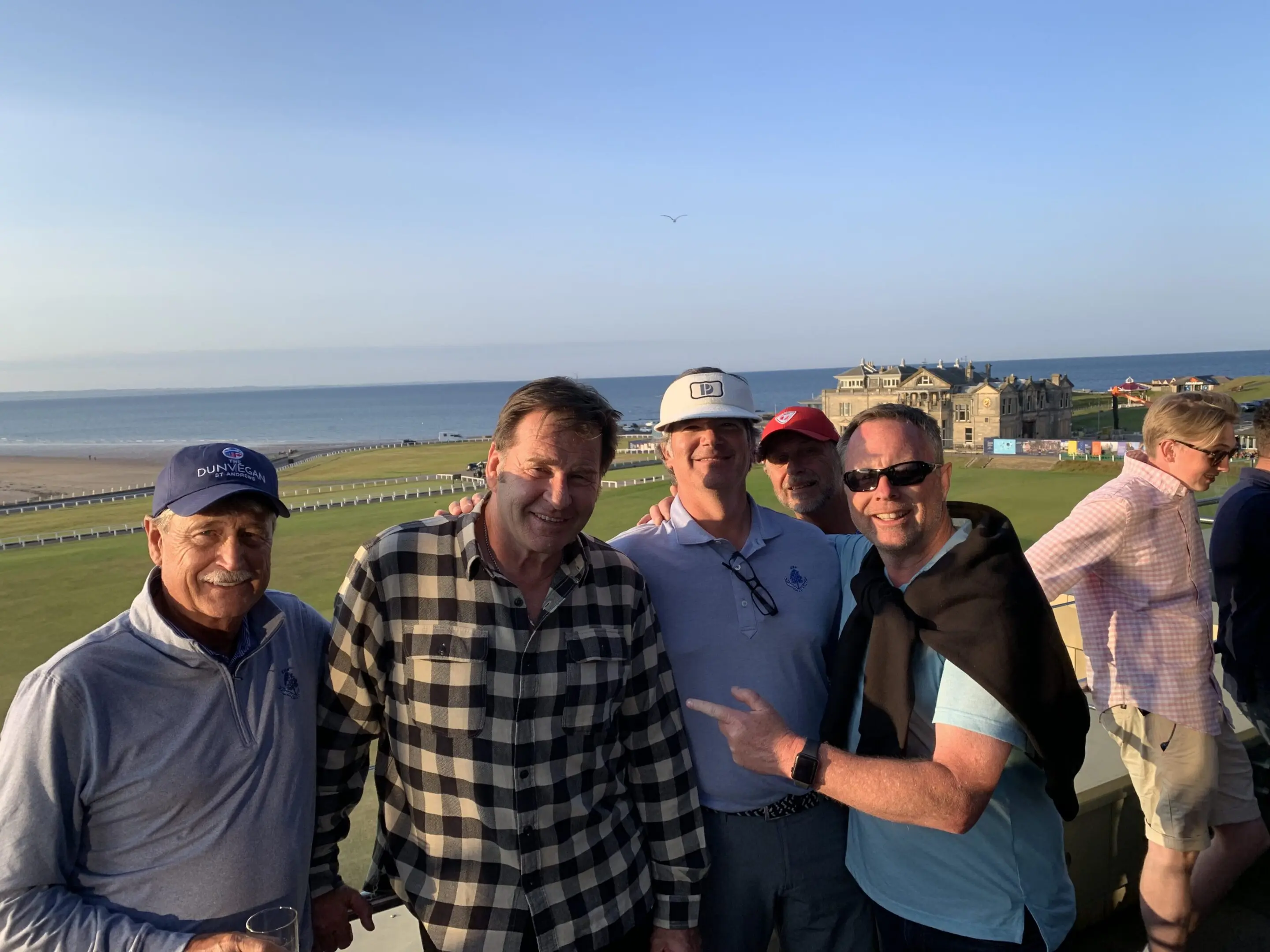 Group of men smiling by the beach.