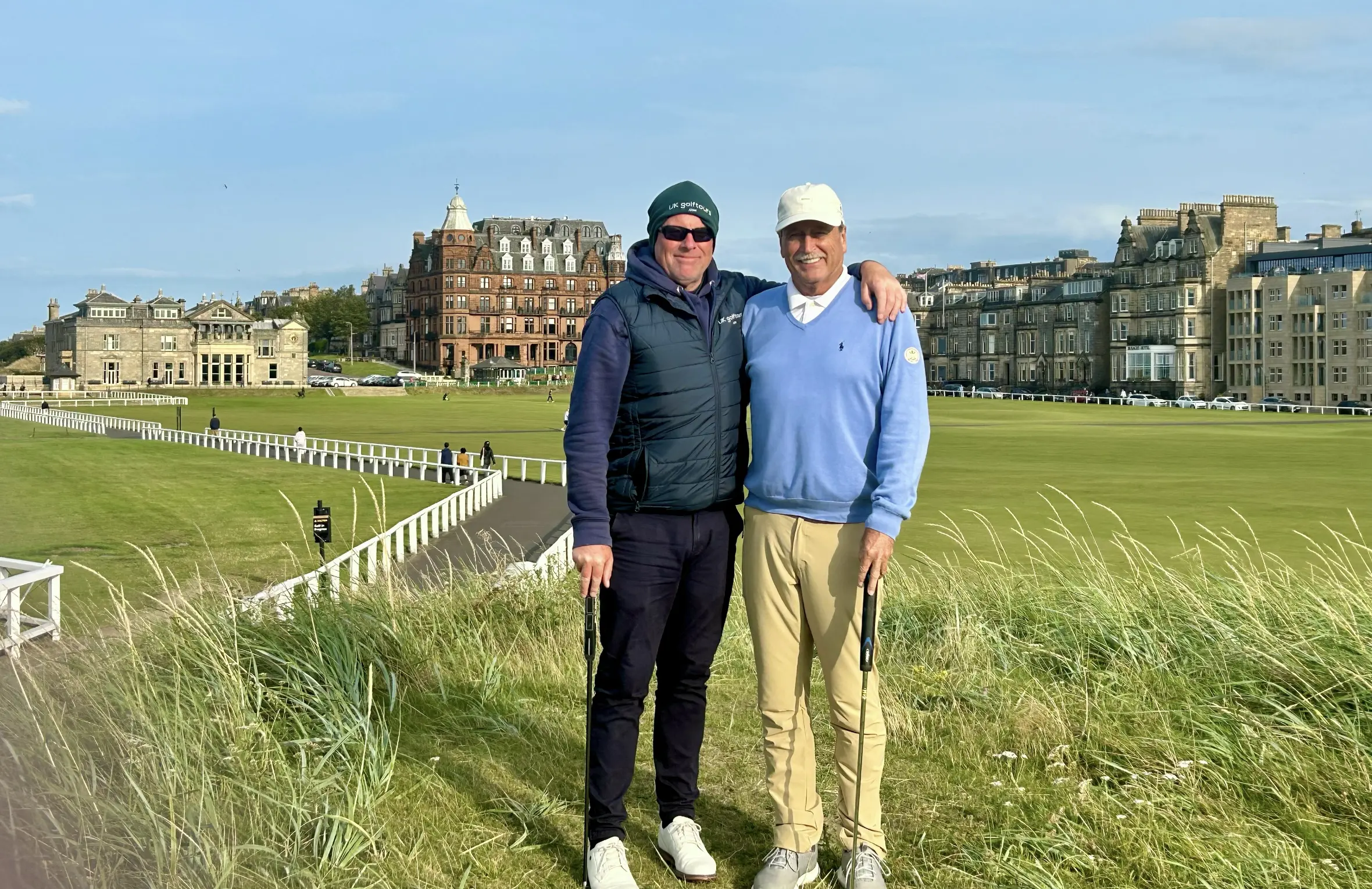 Two golfers posing on a grassy course.