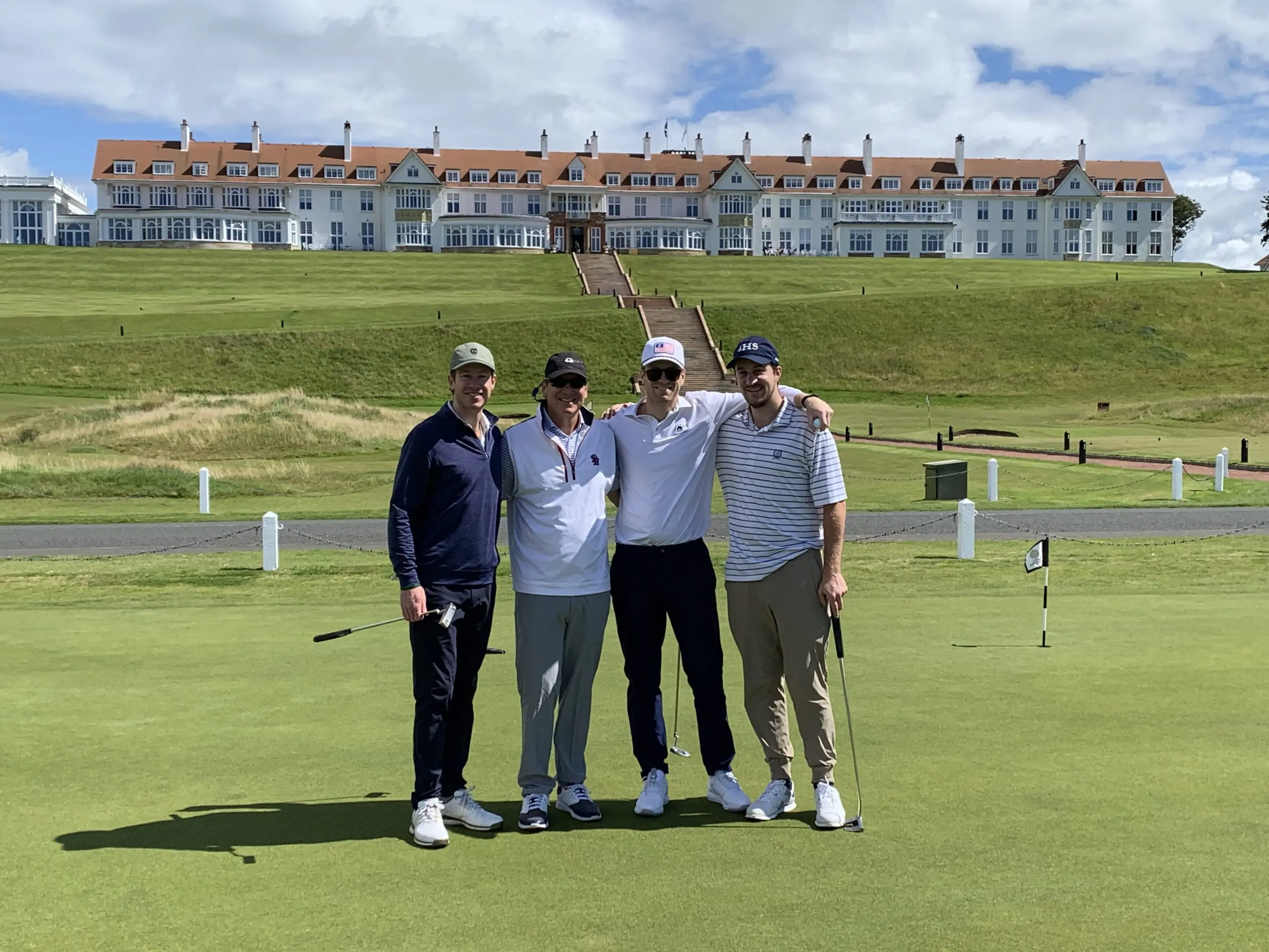 Four men posing on a golf course.