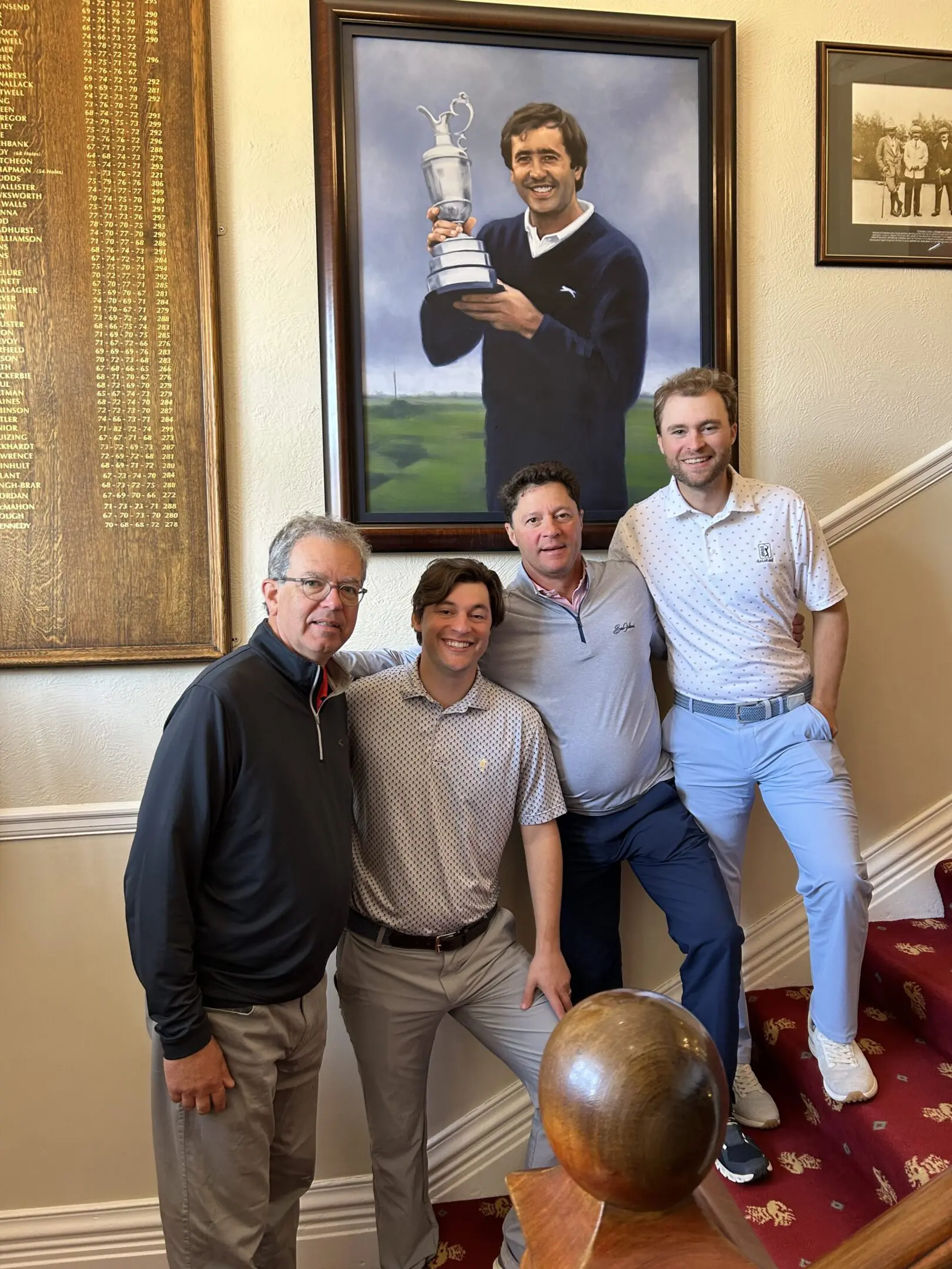 Four men posing by a golf portrait.