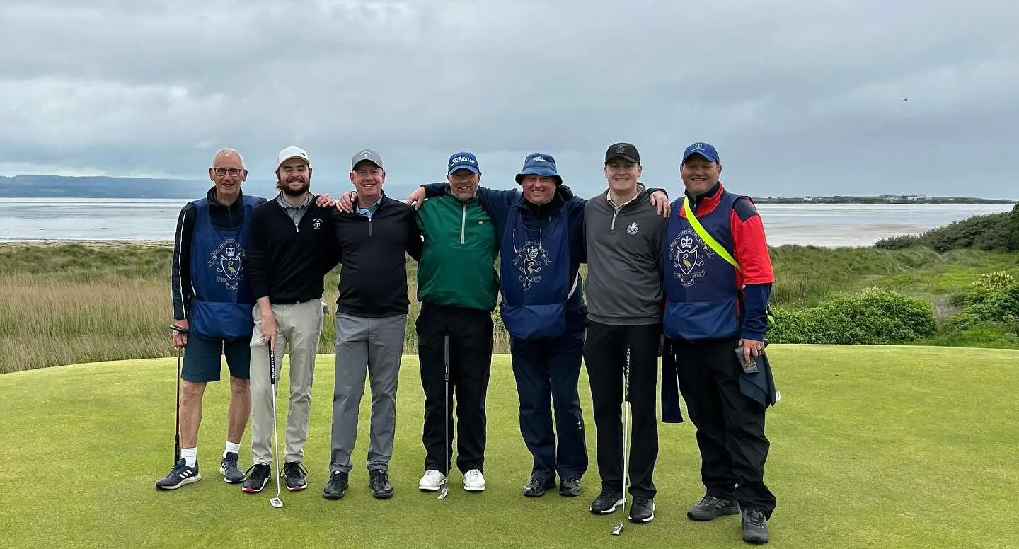 Group of men posing on golf course.