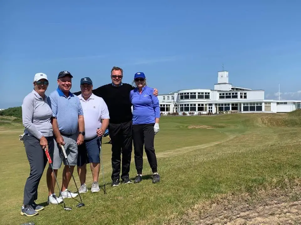 Group of golfers posing on a course.