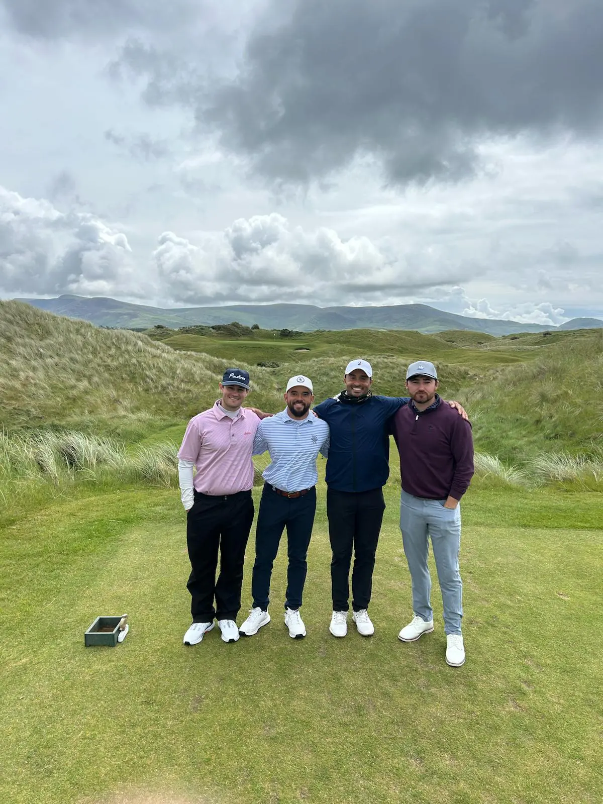 Four men posing on a golf course.