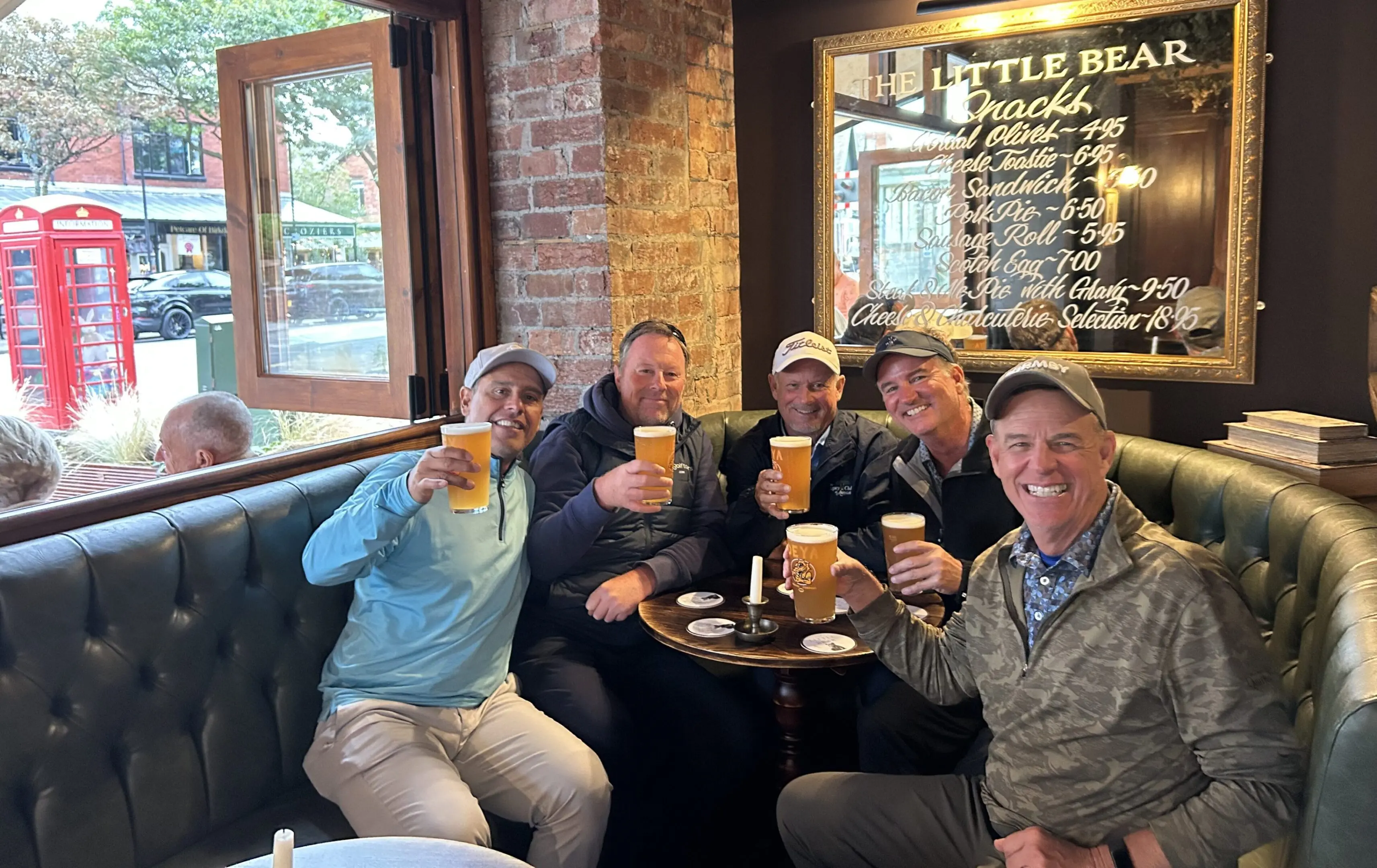Group of friends toasting with beers indoors.