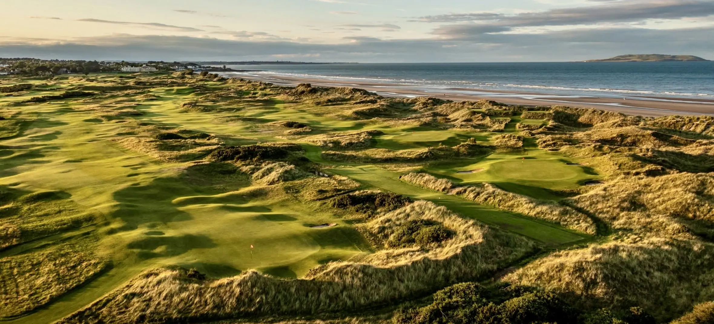 Coastal golf course with dunes and ocean.