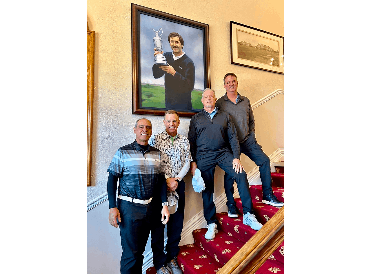 Four men posing on a staircase indoors.