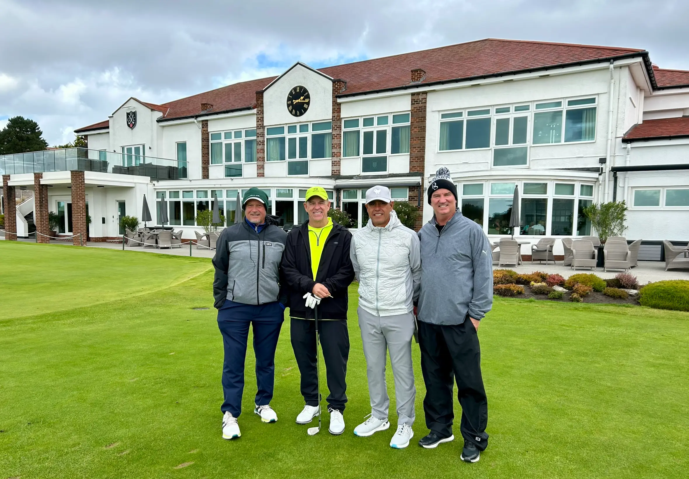 Four people posing at a golf course.