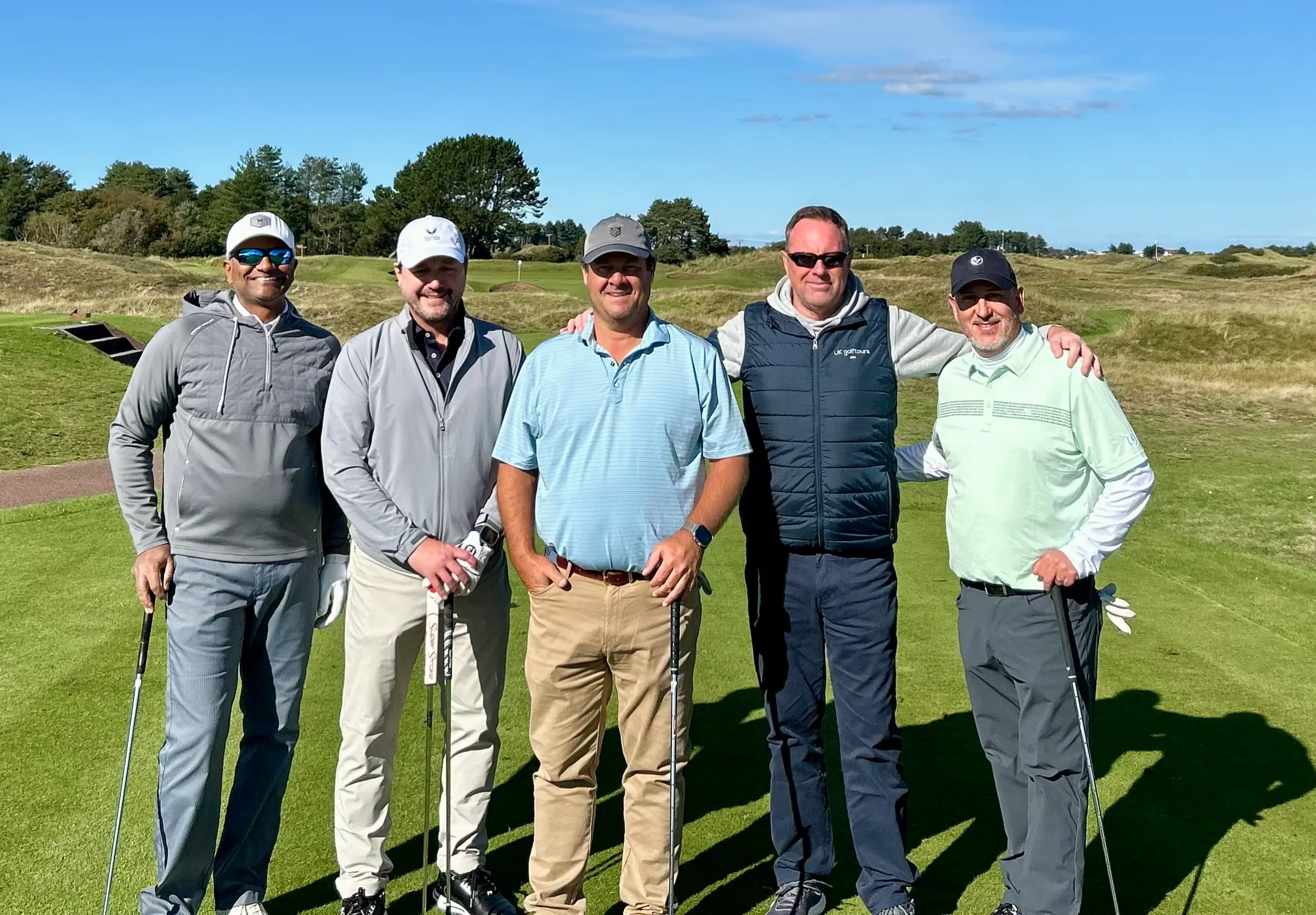 Five men posing on a golf course.