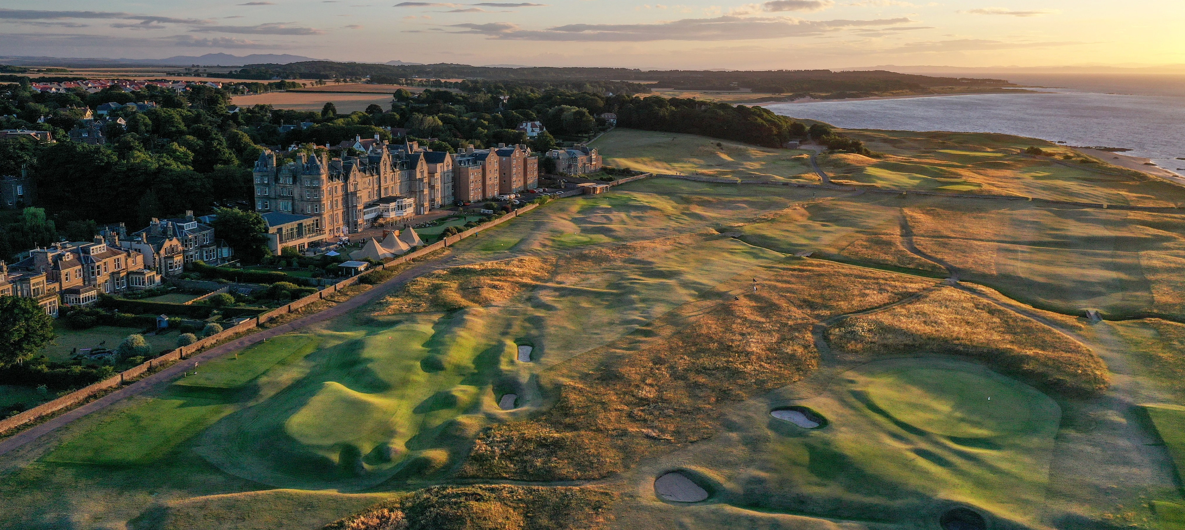 Coastal golf course at sunset, aerial view.