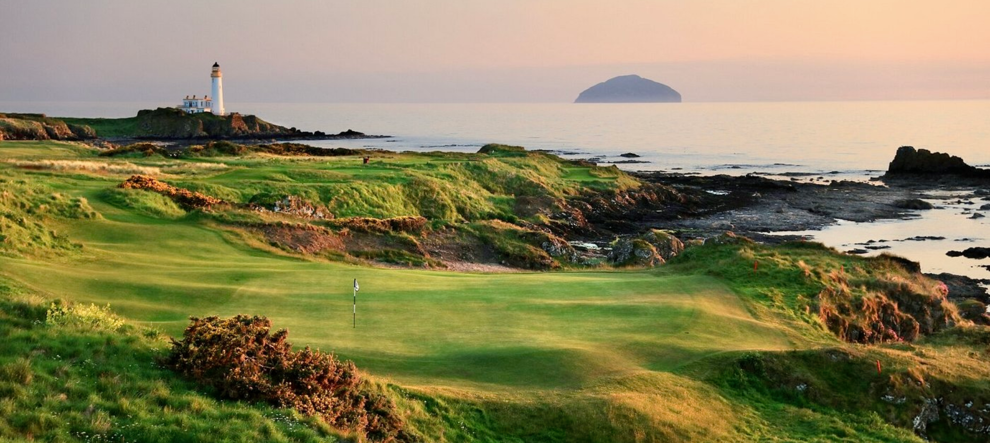 Golf course with lighthouse and ocean view.