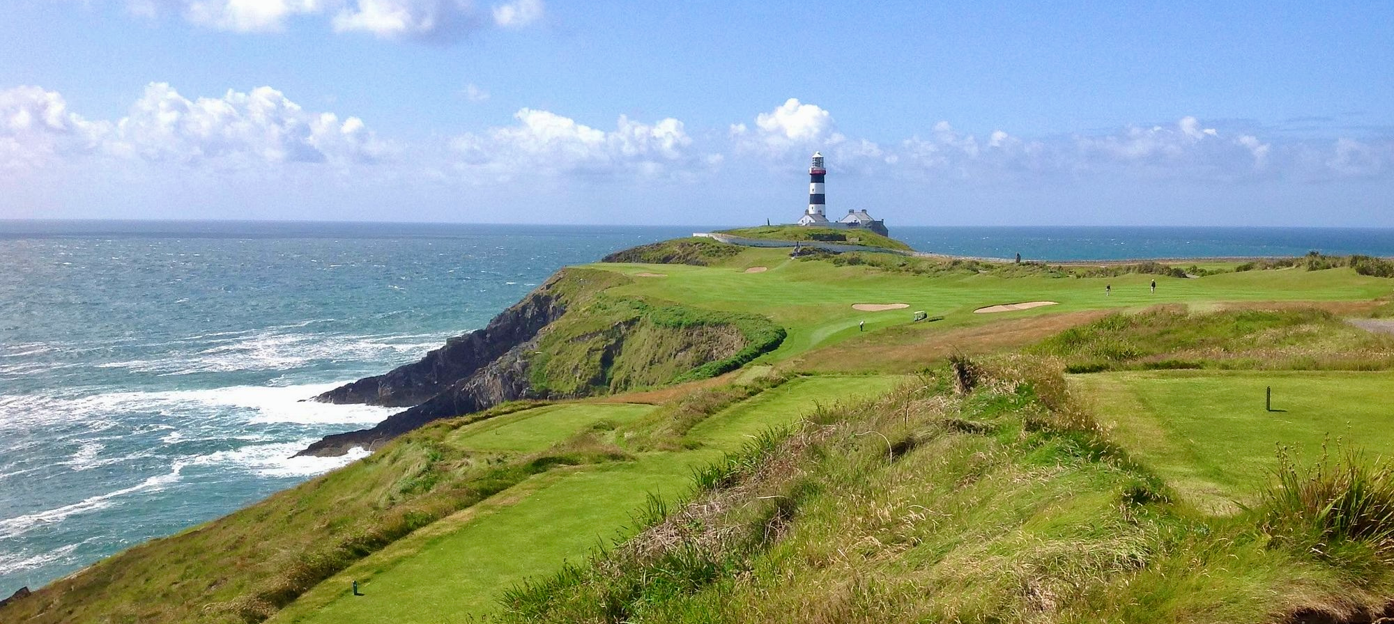 Cliffside golf course with lighthouse and ocean.