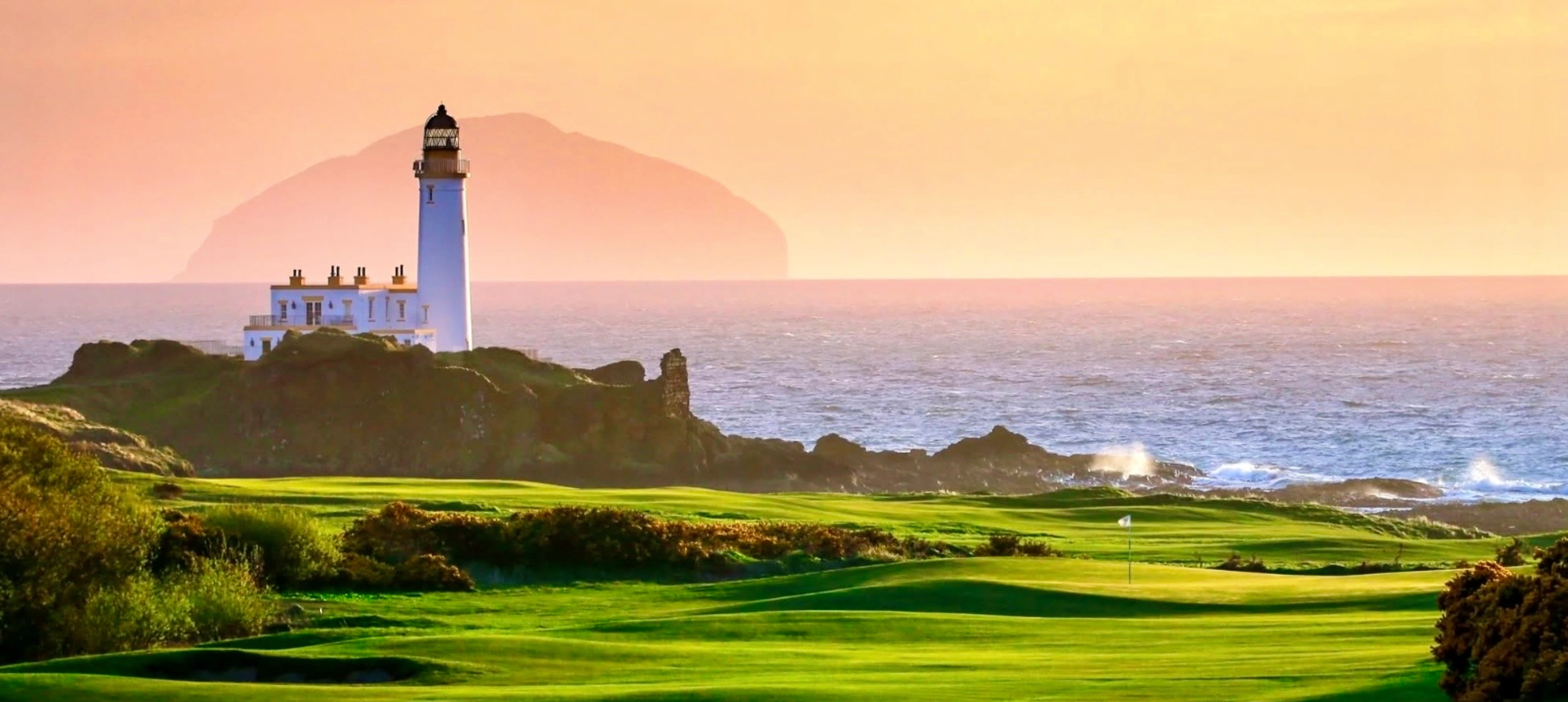 Lighthouse overlooking ocean with distant island.